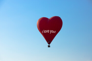 Fototapeta premium Hot air balloon, Red balloon in the shape of a flying heart with the text, I Love you.
