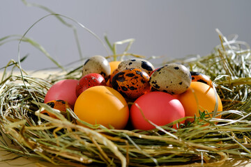 Easter eggs in pink, yellow and orange colors in a nest of grass.
