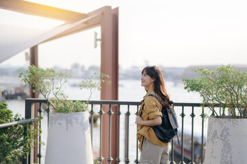 Young Asian woman backpack traveler in express boat pier on the Chao Phraya River in Bangkok. Journey trip lifestyle, world travel explorer or Asia summer tourism concept.