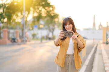 Traveler asian woman in her 30s using smartphone to take a photo while traveling urban street in Bangkok, Thailand