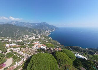 Fototapeta na wymiar drone photo aerial view of Ravello, Amalfi coast, Campania, Lattari mountains in the background and blue sea with passing motorboats