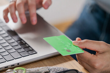 hand placing a credit card on a laptop trackpad, symbolizing a secure online transaction from home