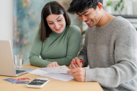 Couple collaborating on financial paperwork with laptop and credit cards on table