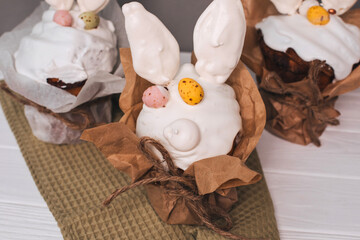 Fototapeta na wymiar Easter cake is decorated with white meringue with ears and chocolate eggs on a light background. Easter background, preparation for the celebrate table. Top view