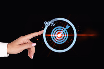 A female hand points to the icon, a dart target. The concept of achieving a goal in business.