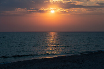 Beautiful setting sun with clouds over the sea, landscape.