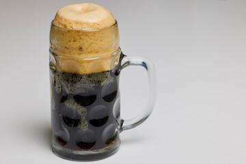a pint of dark beer on a table.