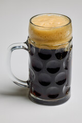 a pint of dark beer on a table.