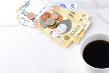 韓国の通貨、ウォンKRW（紙幣と硬貨）と、コーヒーの入ったコーヒーカップ
