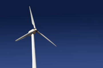 Fototapeta premium Empty copy space windmill. Green energy background. White wind turbine isolated on blue sky.
