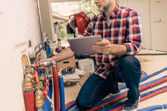 Domestic plumbing water system. Handyman checks whether the installation complies with the design on a tablet.