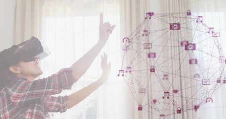 Image of digital interface with globe formed with icons and woman wearing VR headset