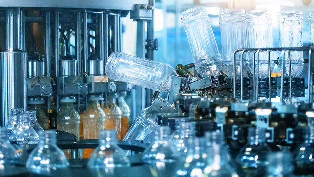 Process of filling plastic bottles inside industrial machine conveyor line in water bottling plant in blue color