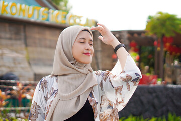 Pretty muslim woman enjoying sun shine at the beach wearing cardigan.