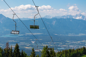 Ski lift in summer with scenic view of majestic mountain range Julian Alps seen from Gerlitzen,...