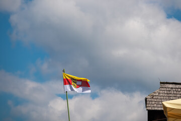 Carinthian flag rippling in the alpine breeze against a blue sky on Gerlitzen Alpe, Carinthia,...