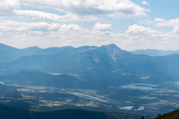 Panoramic view of Lake Faak surrounded by majestic mountain peaks of Karawanks and Julian Alps. Wanderlust on Gerlitzen Alpe,  Carinthia, Austria. Idyllic hiking trail in Austrian Alps in summer