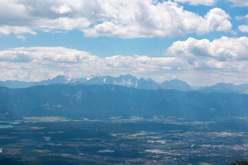 Fototapeta na wymiar Panoramic view of Lake Faak surrounded by majestic mountain peaks of Karawanks and Julian Alps. Wanderlust on Gerlitzen Alpe, Carinthia, Austria. Idyllic hiking trail in Austrian Alps in summer