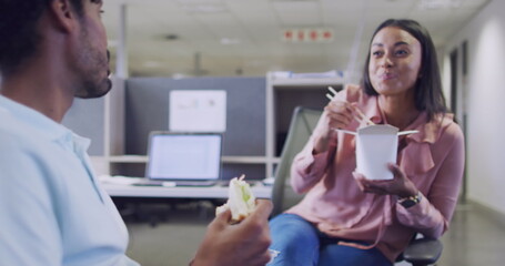 Image of media icons over diverse business people eating in office