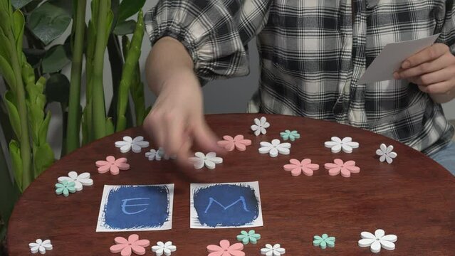 Female arranging the letters EMDR written on blue paper. Potted plant on the side. Eye Movement Desensitization and Reprocessing psychotherapy treatment concept.