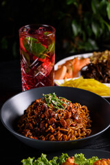 Korean food. Fried Ramen, noodles with vegetables and chicken. on a black wooden background.