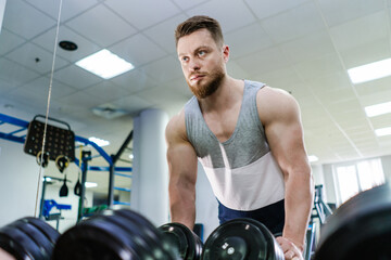 Handsome young man with beard is engaged in gym