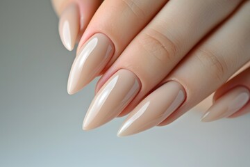 Closeup to woman hands with elegant neutral colors manicure. Beautiful nude manicure on long almond shaped nails. Nude shade nail manicure with gel polish at luxury beauty salon