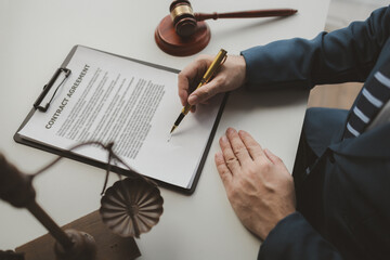 Lawyer is signing contract in the office, Diligent lawyer at work in a law firm, signing official document, Judge gavel with Justice lawyers, lawyer working on a documents, advice and justice concept.