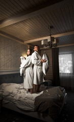A couple in love in bathrobes had a pillow fight in bed. The concept of a morning together