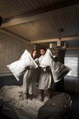 Fototapeta premium A couple in love in bathrobes had a pillow fight in bed. The concept of a morning together