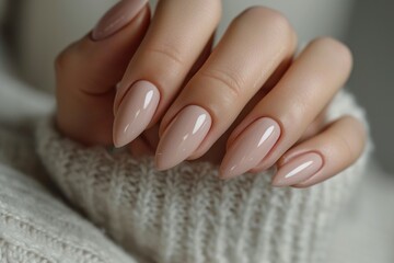 Closeup to woman hands with elegant neutral colors manicure. Beautiful nude manicure on long almond shaped nails. Nude shade nail manicure with gel polish at luxury beauty salon