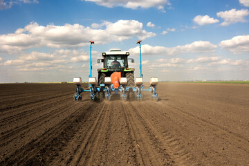 Fototapeta premium Farmer with tractor seeding crops at field