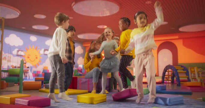 Young Kindergarten Teacher and Cute Multiethnic Children Having Fun. Joyful Kids are Dancing with Their Daycare Pedagogue, Boys and Girls Having a Party at Daycare Preschool