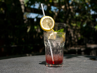 A tropical cocktail with lime, mint and sliced lemon on the stone table