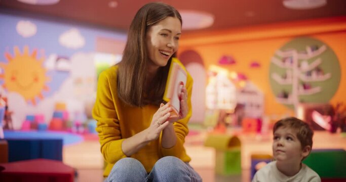 Cheerful Daycare Teacher Using Gaming and Acting Methods to Teach Multiethnic Kids Alphabet in Kindergarten. Small Cute Boys and Girls Getting Basic Reading and Writing Skills, Learning Alphabet