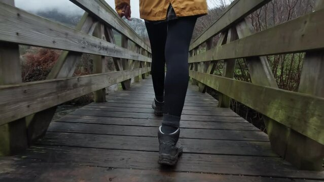 Slow Motion Young  lady crossing a timber footbridge over a steam in countryside