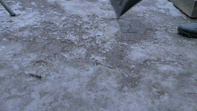 Street cleaner woks with shovel to remove snow and ice from road, ta make it safe for walking