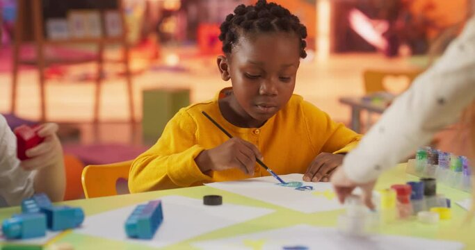 Portrait of an Adorable Stylish Black Girl Using Watercolor to Draw a Colorful Painting. Cheerful African Child Spending Productive Time in Preschool, Learning to Paint in Art Class