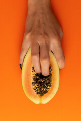 Two female fingers in papaya fruit on vivid background. Sex concept.