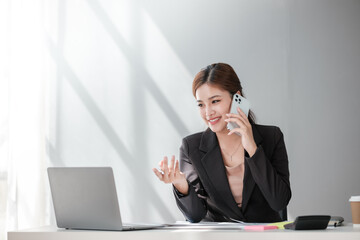 Cheerful Successful Asian Business woman using calculator and laptop for doing math finance on an office desk, tax, report, accounting, statistics, and analytical research concept 