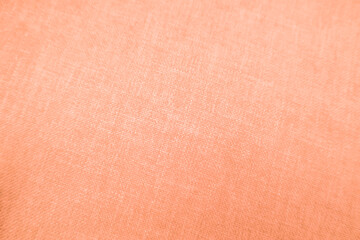 Background. Color of the year 2024 peach fuzz. Rough burlap fabric peach color. Structure of the fabric with natural texture. Cloth backdrop.