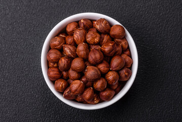 Delicious hazelnut whole, raw, without shell, on a dark concrete background