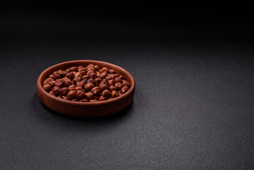 Delicious hazelnut whole, raw, without shell, on a dark concrete background