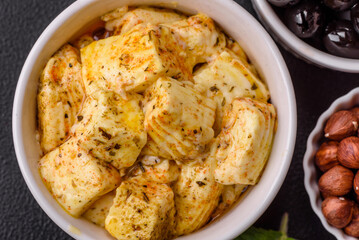 Delicious soft white feta cheese with salt, spices and herbs on a dark concrete background