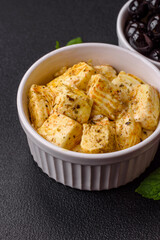 Delicious soft white feta cheese with salt, spices and herbs on a dark concrete background