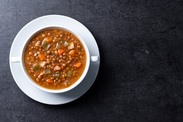 Lentil soup with vegetables in bowl on black background. Top view. Copy space