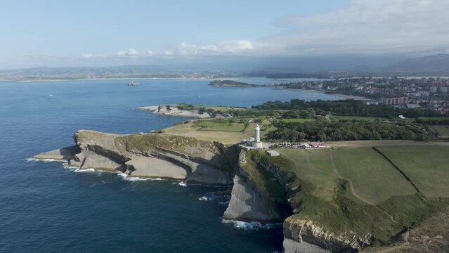 Lighthouse at Grand Cape, Cabo Mayor in Santander Spain with ocean cliffs, Aerial orbit around shot