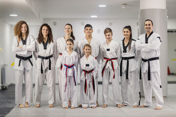 Fototapeta na wymiar Team of taekwondo athletes standing confidently at martial art school and smiling at the camera.
