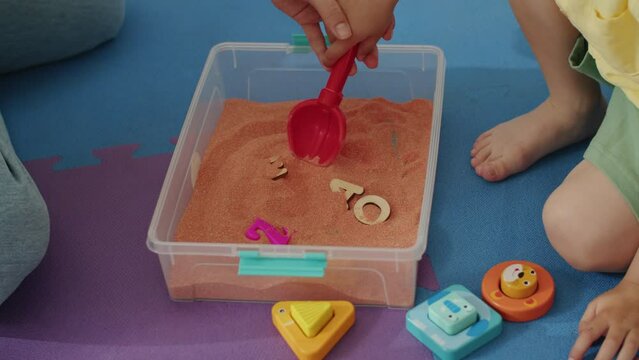 Therapist and child using a sensory sand tray for tactile learning. Sensory play and fine motor skill development concept for design and print.