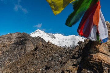 Сairn, pile of stones, Buddhist prayer flags and snow capped mount Cho Oyu of the Himalayas during EBC Everest Base Camp or Three Passes trekking. View from Gokyo Ri, Nepal.